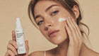 Woman smoothing REST sensitive skin overnight cream into cheek with fingertips, calm skin close-up