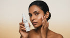 Woman smoothing EVEN dark spot correcting cream into cheek with fingertips, even skin tone close-up
