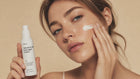 Woman smoothing REST sensitive skin overnight cream into cheek with fingertips, calm skin close-up