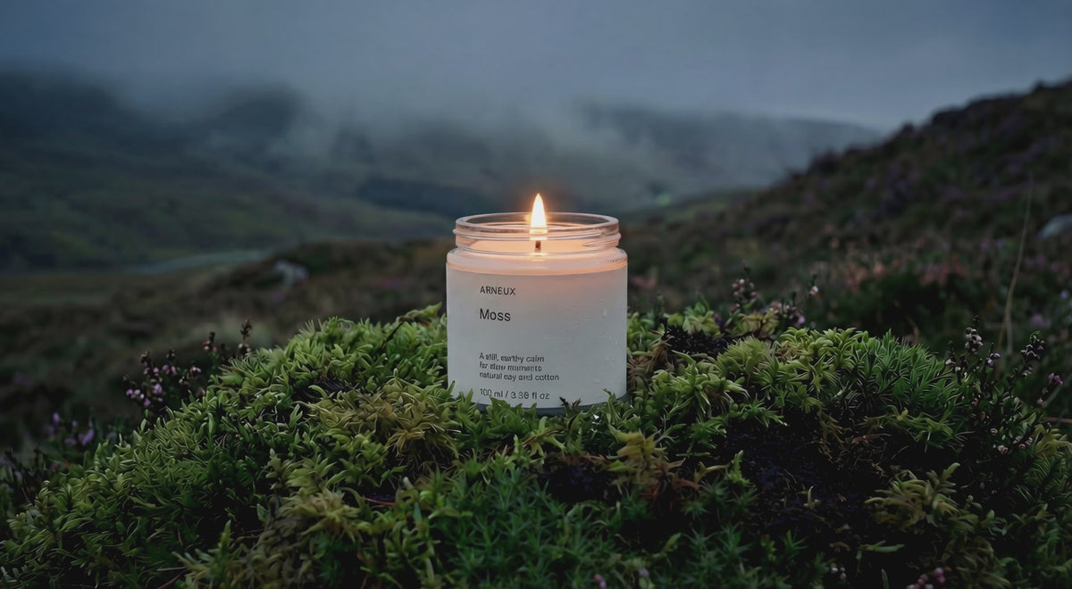 MOSS soy wax travel candle burning on vivid green moss bed in dramatic misty highland landscape