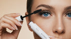 Woman sweeping DEFINE mascara wand along lower lash line, close blue eye view showing lash definition