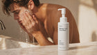 Man rinsing CLEAR blemish face wash under running water at sink, no-residue rinse-off formula