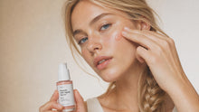 Woman dotting REVIVE peptide serum onto cheekbone with fingertip, dewy firm skin close-up