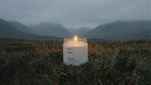 EMBER soy wax travel candle burning alone in dramatic moody Scottish highlands landscape at dusk