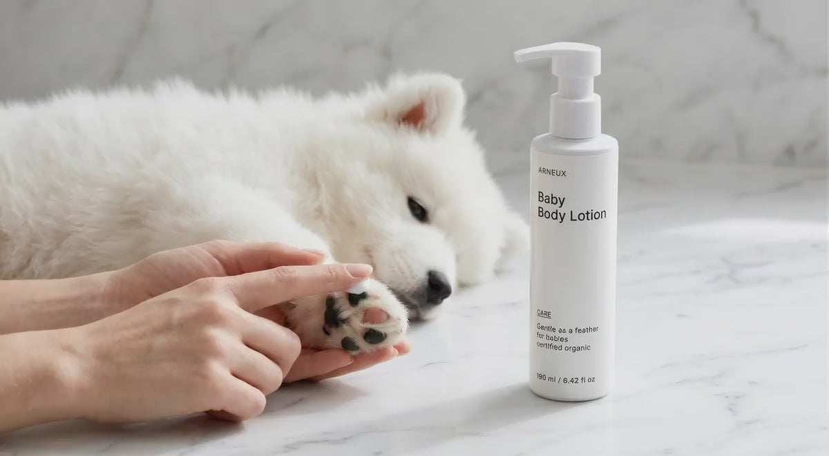White fluffy puppy sleeping peacefully beside CARE baby body lotion bottle, gentle hypoallergenic formula